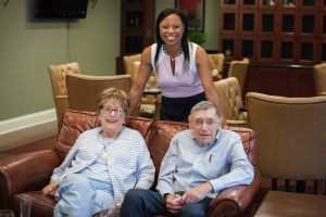 Nicole Smith, Director of Community Programming, poses with residents in the Cherry Blossom Lounge.